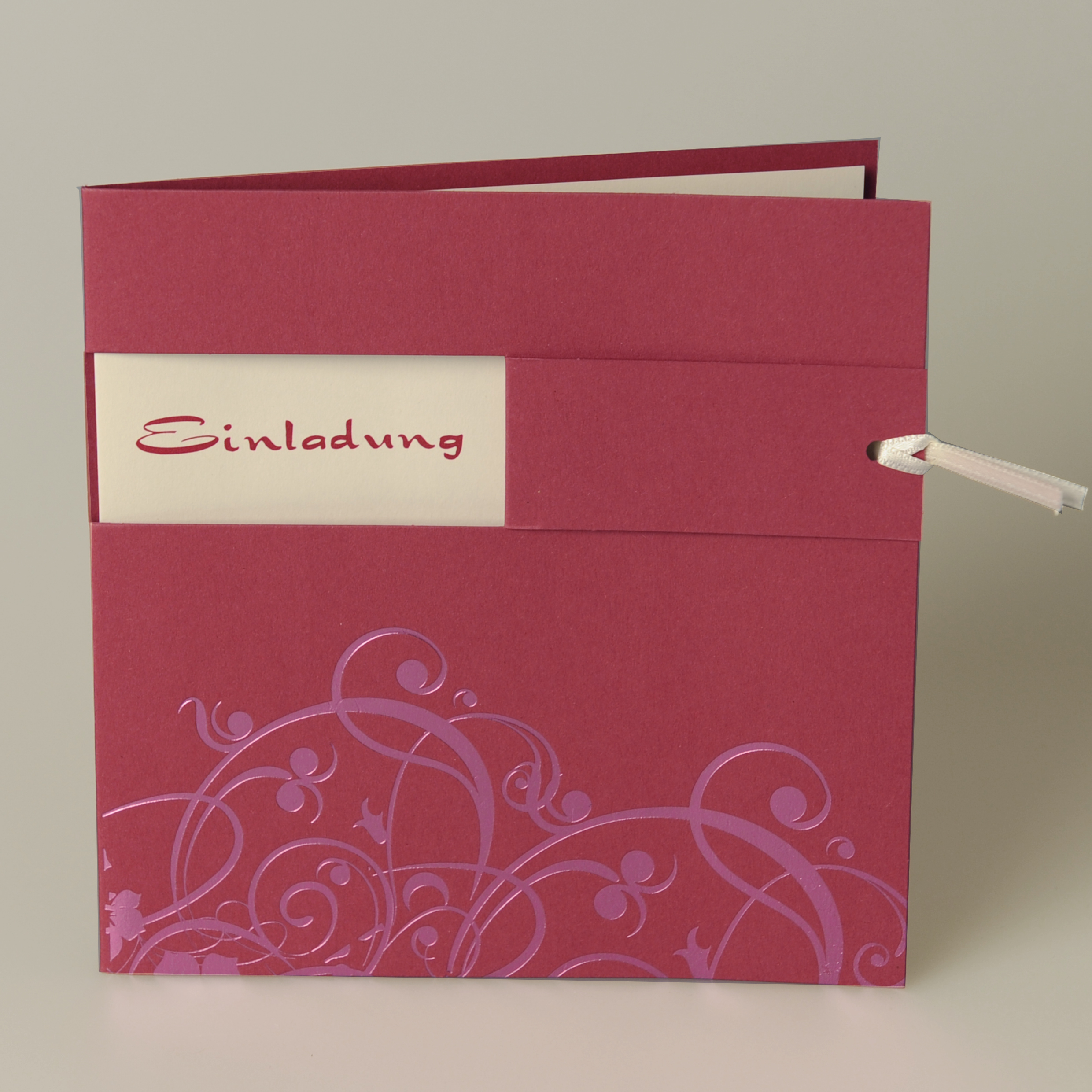 Pinke quadratische Karte mit gedruckten Ornamenten im unterem Bereich der Karte, cremefarbigem Satinband, Einstecker und Kuvert creme. Pinke quadratische Karte mit gedruckten Ornamenten im unterem Bereich der Karte, cremefarbigem Satinband, Einstecker und Kuvert creme.
