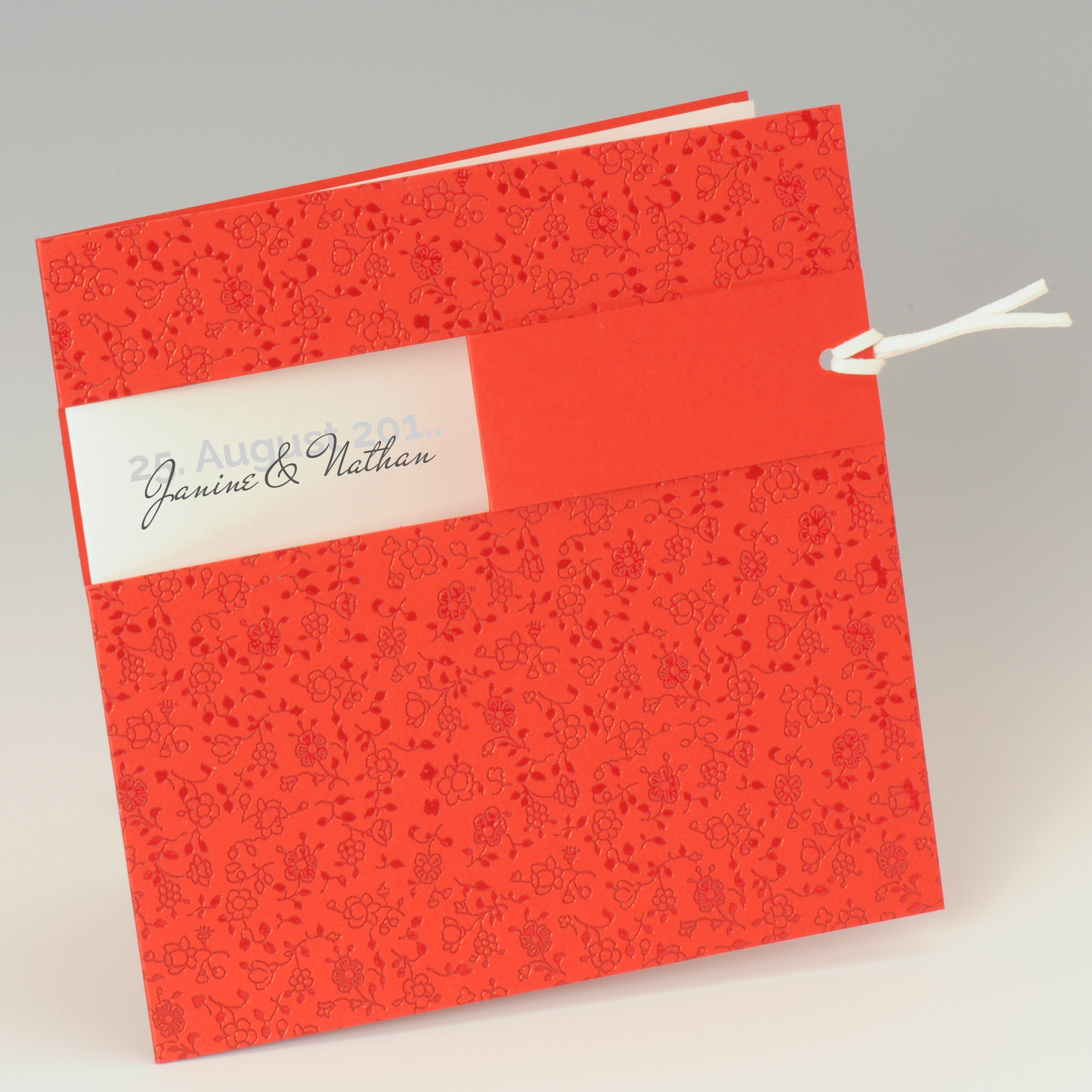 Rote quadratische Karte mit foliengeprägten Ornamenten und Lederband