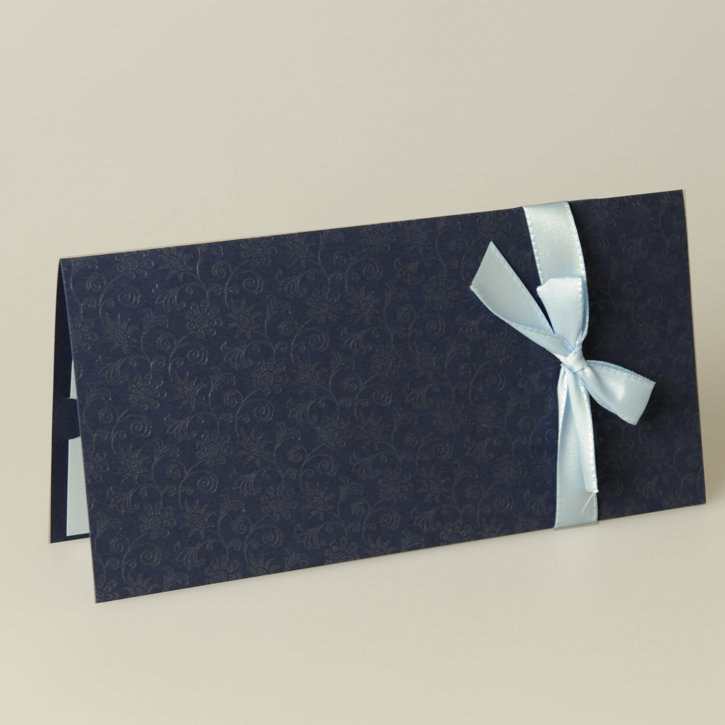 Dunkelblaue Einladungskarte mit geprägten Ornamenten und hellblauem Band.